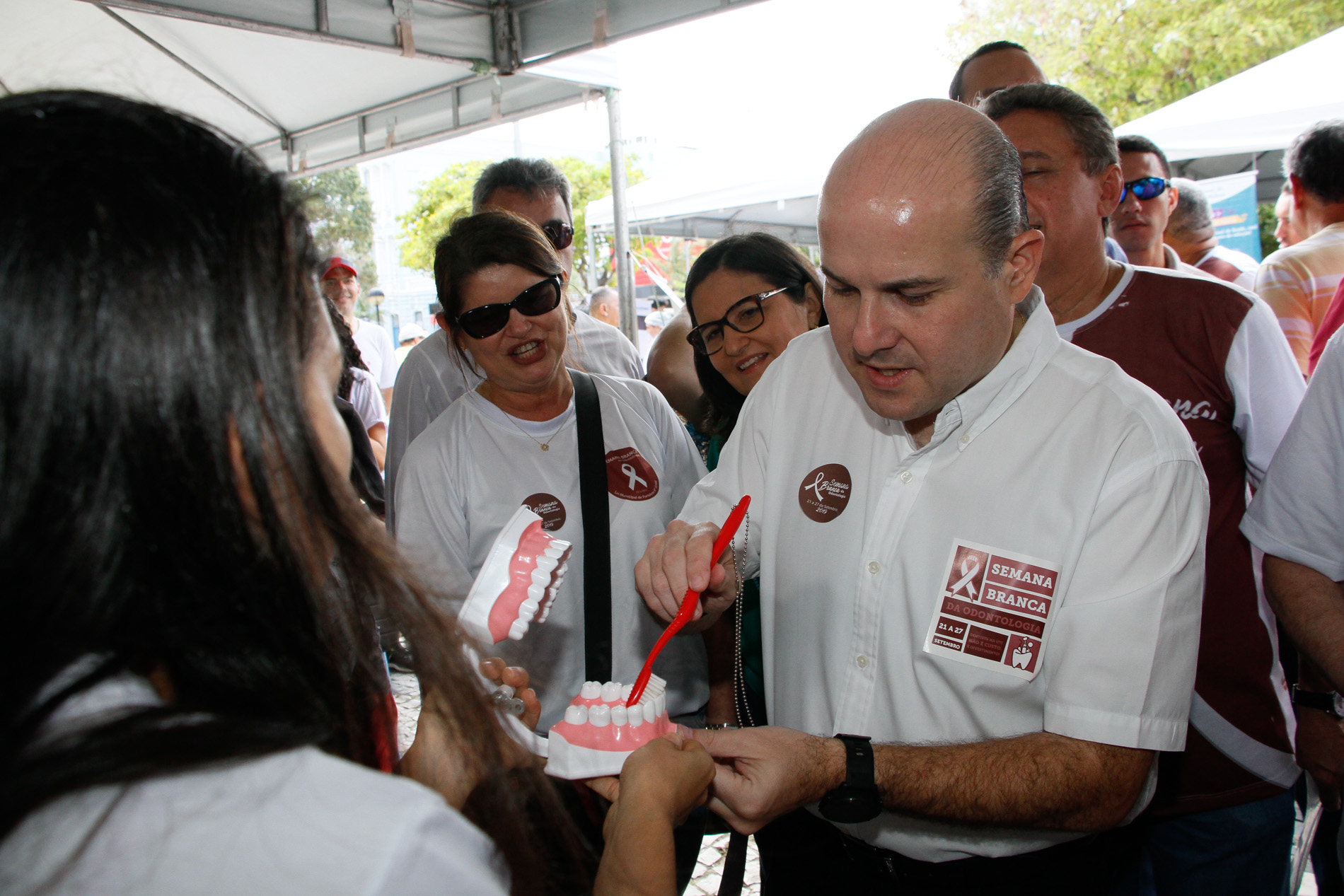 prefeito conversa com mulher que mostra um molde de dentes, usado para ensinar a escovar os dentes